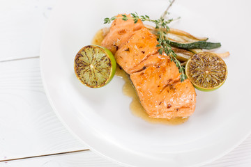 Salmon with lime and grilled vegetables witn sauce on white plate. Healthy food concept