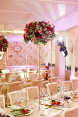 A cozy banquet room in a restaurant during a wedding celebration. Served tables decorated with beautiful bouquets of flowers