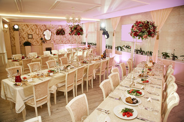 Banquet room during the celebration of the wedding. Served tables decorated with large bouquets of fresh flowers.