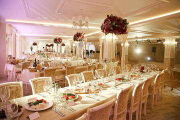 Large banquet hall during the wedding celebration decorated with decorative elements and a bouquet of flowers