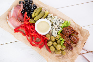 Food set of cucumbers, olives, cheese, blue cheese, sauce, tomatoes on wooden table