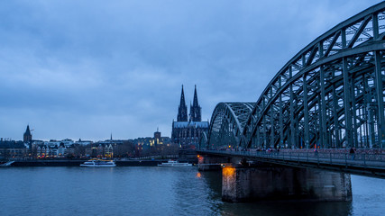 view of river Rhine and city of Cologne at dusk, train bridge and cathedral