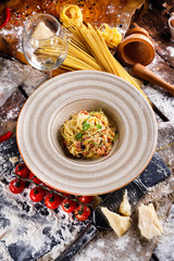 Pasta Carbonara with Parmesan on a white plate. Restaurant food at the wooden table