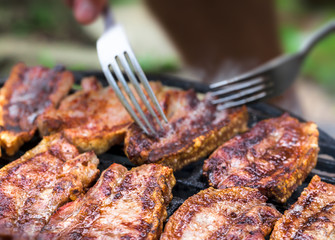 Barbeque outdoors close up arrangement with pork meat grilled bacon and smoke with two metal forks