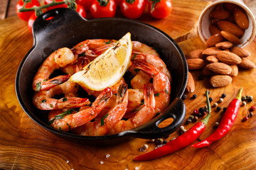 Spicy shrimp in a pan with garlic, cilantro and pepper, next ingredients for cooking, tomatoes