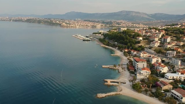 Scenic aerial bird view at morning coastal village near Split in Croatia, calm and quite tourist vocational hotel seafront under green mountains in Europe. Early morning.