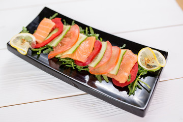 Fish diet< fresh vegetables and salmon on black plate with rucola, and lemon
