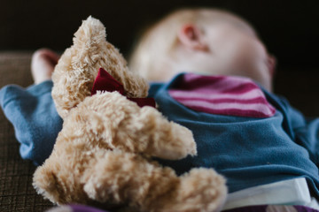Close up of a toddler girl sleeping with a stuffed teddy bear
