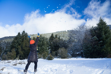 Action moment of a girl throwing snow balls in the air with her back facing the camera