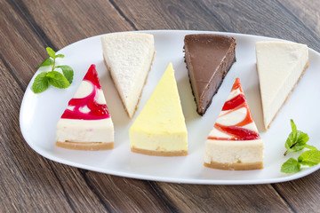 Slices of various cheese cakes on white plate. Sugar desserts, food concept 