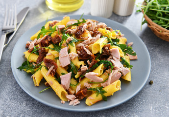 Penne pasta with tuna chunks, rucola and dry tomatoes