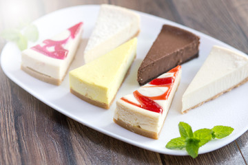 Slices of various cheese cakes on white plate. Sugar desserts, food concept 