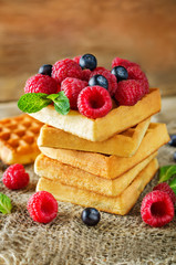 Waffeles with berries and mint leaf on a wood background