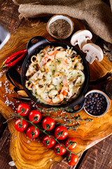 Delicious seafood in white sauce on a metal black plate, a number of products for cooking, tomatoes, champignons.