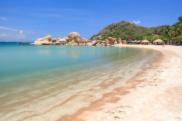 lagoon with clear blue water, tropical greenery and rocks with boulders