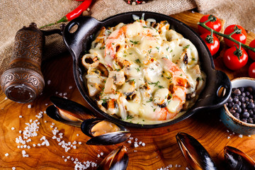 Delicious seafood in white sauce on a metal black plate, a number of products for cooking,...