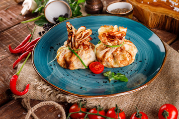 Pancakes with salmon, cream cheese and herbs. Bags tied with dill on a blue plate