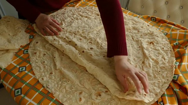 a woman prepares to eat thin yufka bread in the kitchen,
