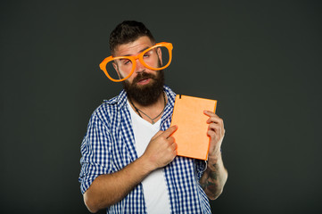 Hipster bearded man funny eyeglasses hold notepad or book. Read this book. Comic and humor sense. Courses adult education. Self education concept. Literary club. Reading book as hobby. Study is fun