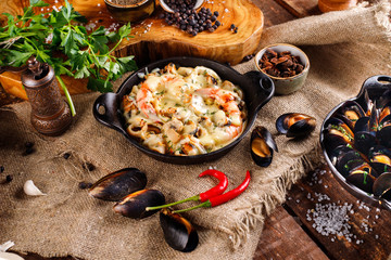 Tasty seafood in white sauce on a metal black plate.