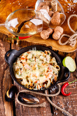 Tasty seafood in white sauce on a metal black plate.