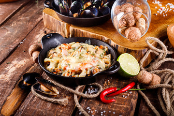 Tasty seafood in white sauce on a metal black plate.