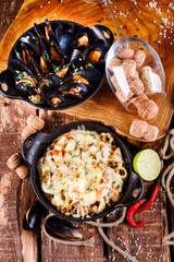 Tasty seafood in white sauce on a metal black plate.