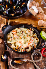 Tasty seafood in white sauce on a metal black plate.