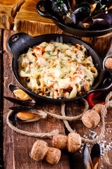 Tasty seafood in white sauce on a metal black plate.