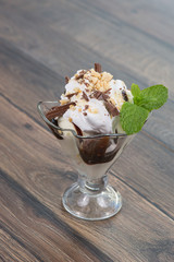 Fresh ice cream witn chocolate and fruits on wooden plate
