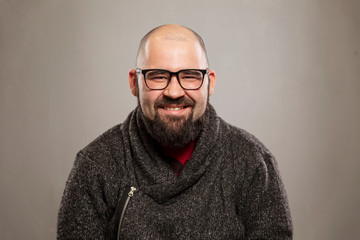 Young bald man laughs, gray background