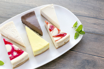 Pieces of various cheese cakes on plate in cafe. Food photo, sugar desserts concept