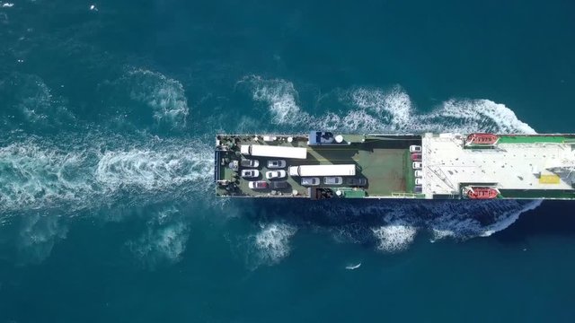 Medium sized Ro-Ro (Roll on/off) ship roaring across The Mediterranean Sea with cars and trucks seen on the upper deck.