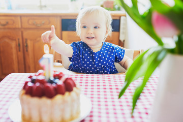 Happy baby girl in blue dress celebrating her first birthday