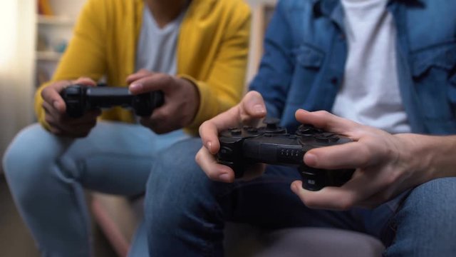 Multiracial friends playing computer games, closeup on hands with joysticks