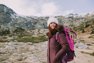 Naklejka premium mountaineer girl with a backpack on her back looks around the high hills and the green meadows