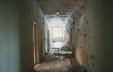The interior of an abandoned old building. A long corridor with entrances to rooms without doors.