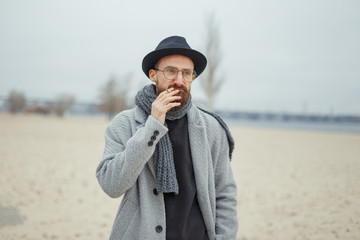 Portrait of a smoking man in a coat and hat.