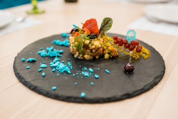 Fresh tartar with salmon, cucumber and black caviar on dark desk plate, close up
