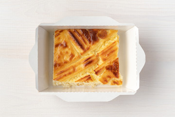 Sweet ruddy casserole in paper box on wooden background