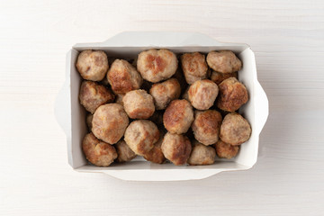 Grilled meatballs in paper lunchbox on wooden background