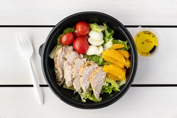 Healthy food to go in round lunch box on wooden background. flat lay..