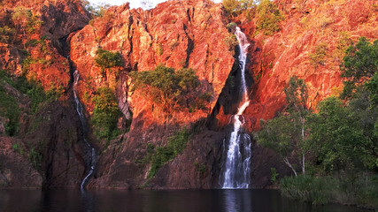setting sun turns the cliffs at wangi waterfalls in litchfield national park a brilliant red