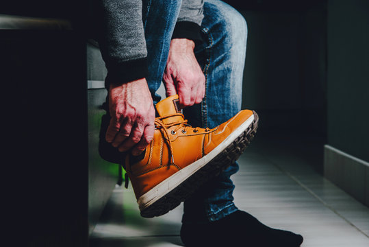 Putting Shoes In The Hall, Preparing For The Exit. The Man Puts On A Foot A Brown Shoe. The Concept Of Leaving Home, Leaving The Premises.