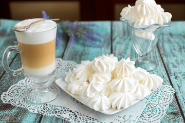 White marshmallows and bizet with coffee latte on the table in cafe. Delicious sugar dessert. Food photo concept