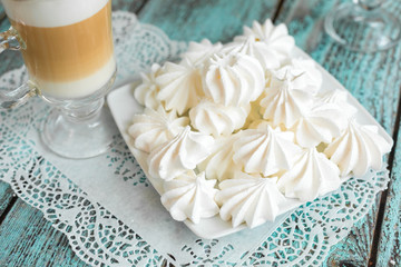 White marshmallows and bizet with coffee latte on the table in cafe. Delicious sugar dessert. Food photo concept