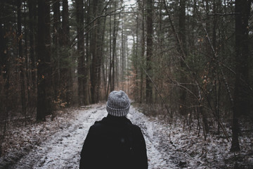 Obraz premium Girl in wool hat looking ahead on a trail in the woods