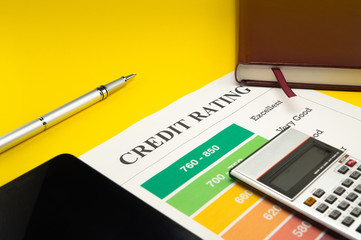 Credit rating on a yellow table, pen, calculator, notebook