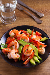 Shrimp, Avocado, Tomato and Cilantro Salad. Grilled prawns on black plate