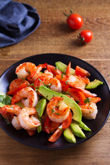 Shrimp, Avocado, Tomato and Cilantro Salad. Grilled prawns on black plate
